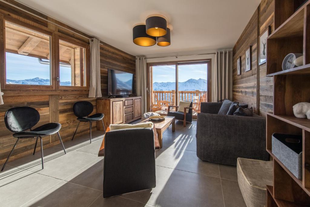 un salon avec un canapé, des chaises et une télévision dans l'établissement ODYSSEE A201 Vaste appartement en vieux bois sur les pistes, vue panoramique, à La Toussuire