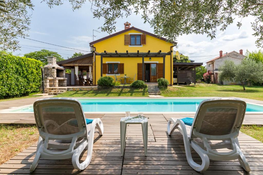 a yellow house with two chairs and a pool at Villa Nada in Buje