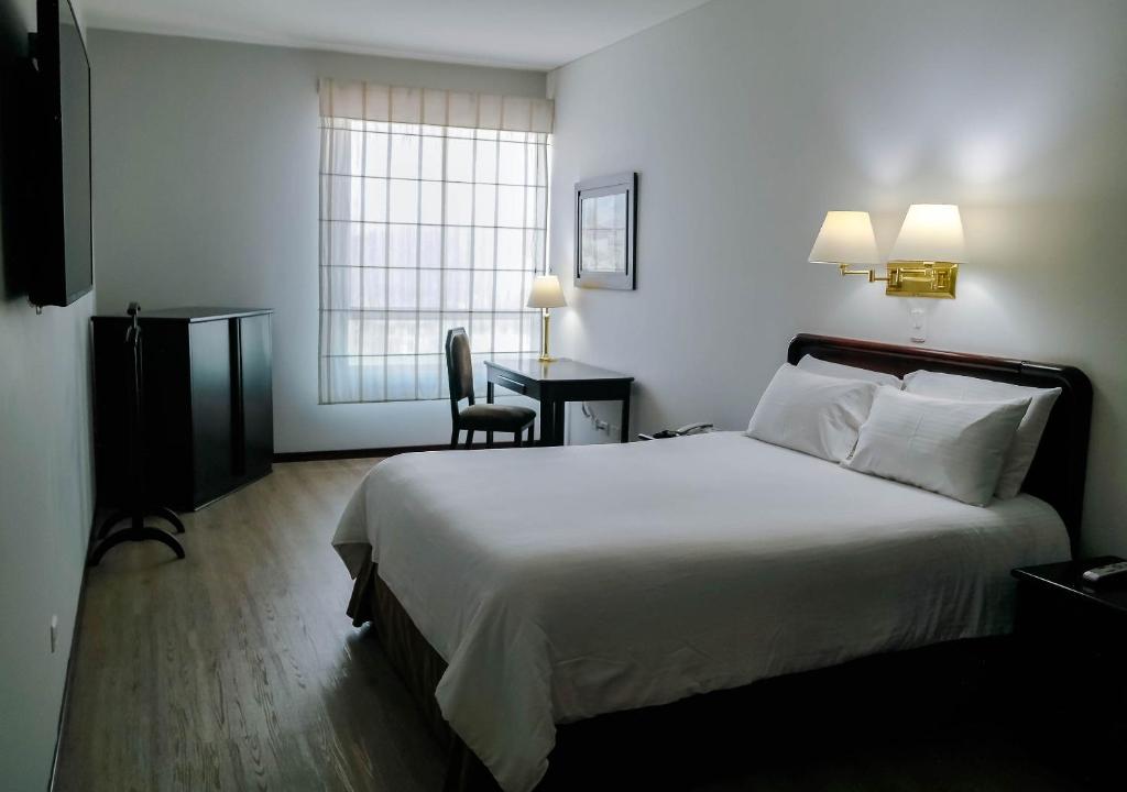 Pokój hotelowy z dużym łóżkiem i biurkiem w obiekcie Hotel Internacional La Triada w mieście Bucaramanga
