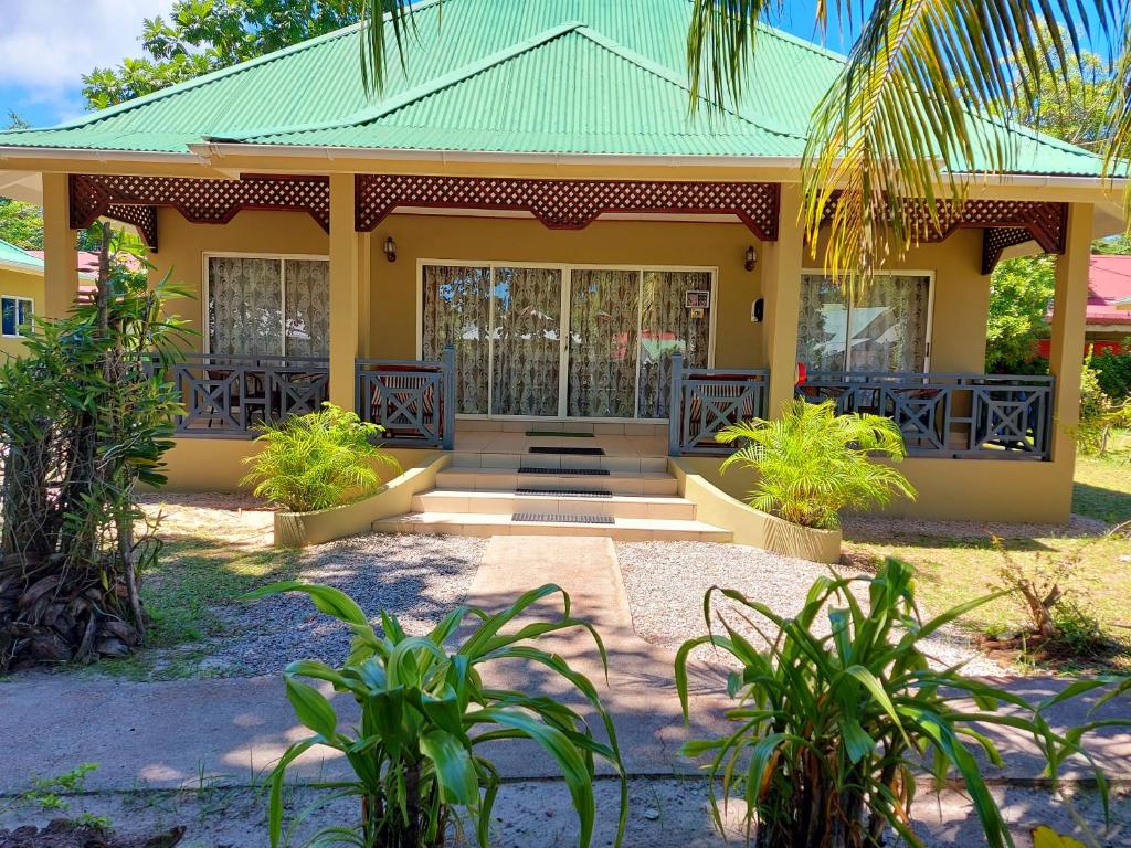 une maison jaune avec un toit vert dans l'établissement Hostellerie La Digue, à La Digue