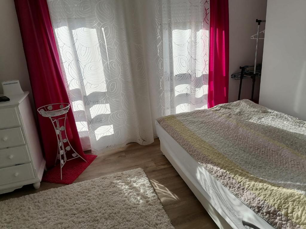 1 dormitorio con cortinas rojas, 1 cama y vestidor en Dreams Apartments, en Niš