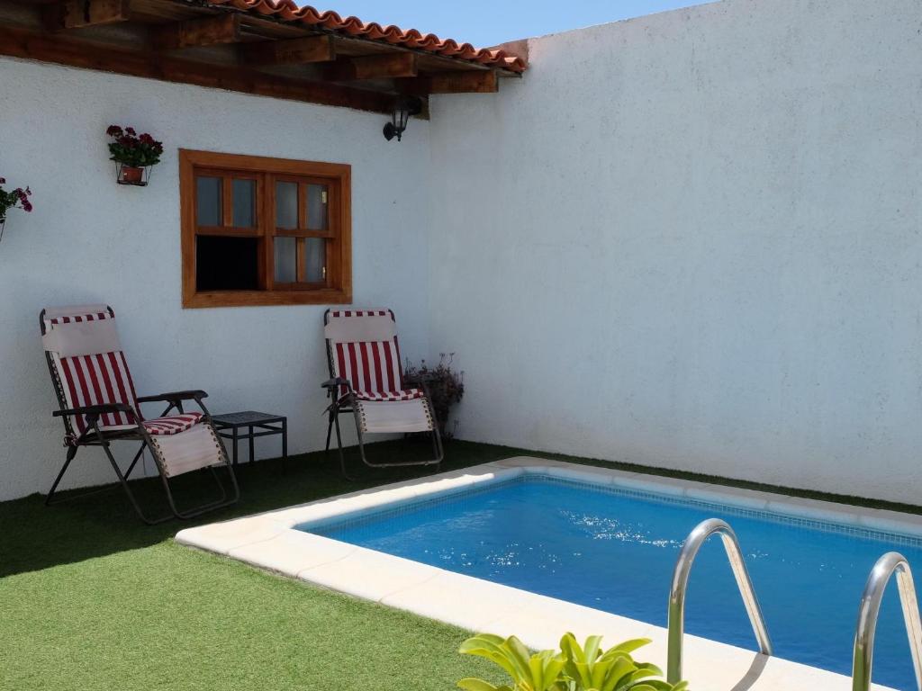 eine Terrasse mit 2 Stühlen und einem Pool in der Unterkunft Casa Samuel in Granadilla de Abona
