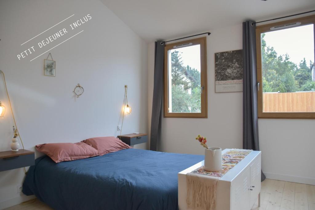 a bedroom with a blue bed and two windows at Le Bivouac - Toulouse in Toulouse