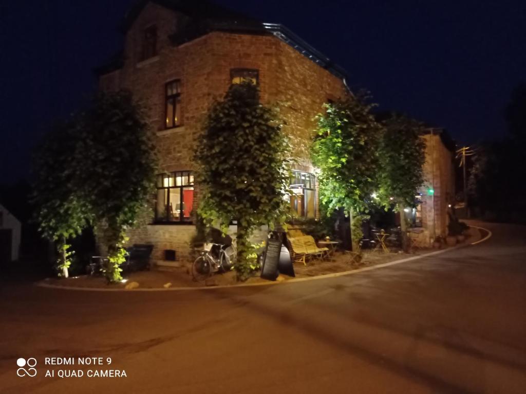 un bâtiment avec des arbres devant lui la nuit dans l'établissement L'ancienne Boulangerie, à Durbuy