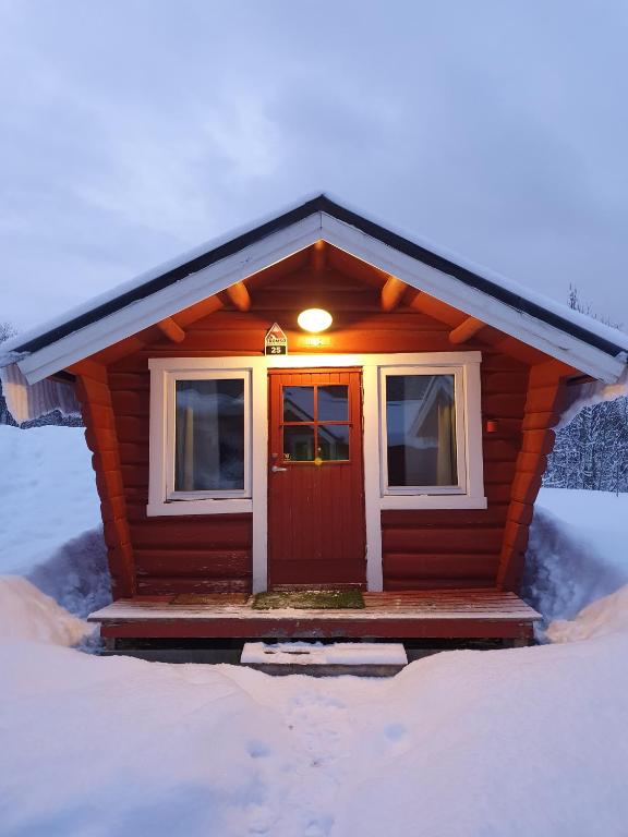 a small house with a red door in the snow at Tromsø Lodge & Camping in Tromsø