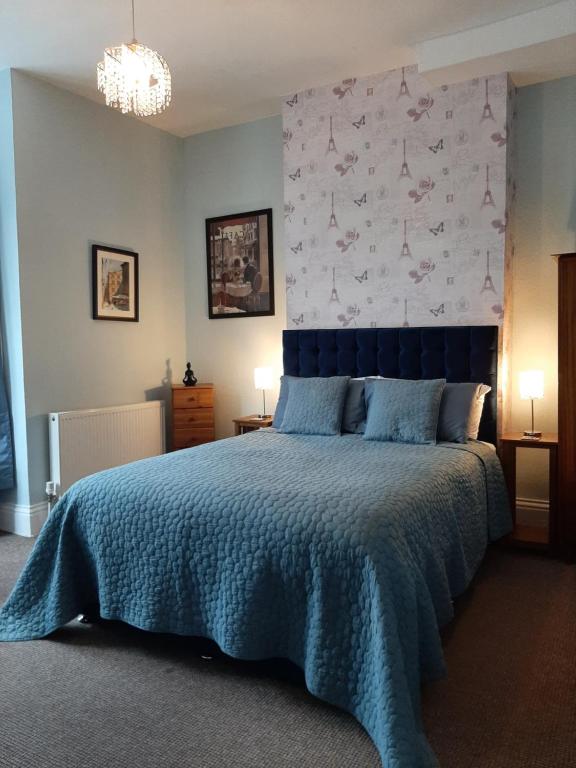 ein Schlafzimmer mit einem großen Bett mit einer blauen Decke in der Unterkunft Rosemead Guest House in Paignton
