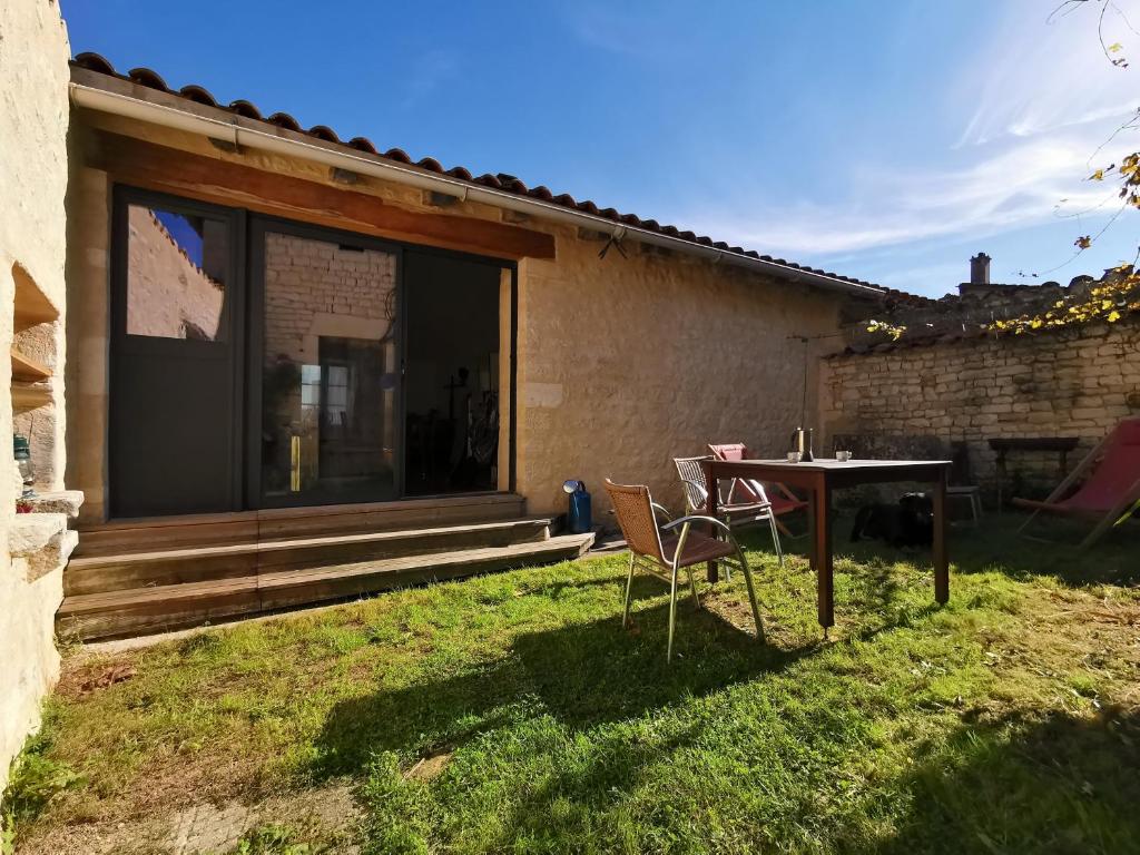 eine Terrasse mit Tisch und Stühlen in einem Hof in der Unterkunft La maison de Thomas in Saint-Amant-de-Boixe