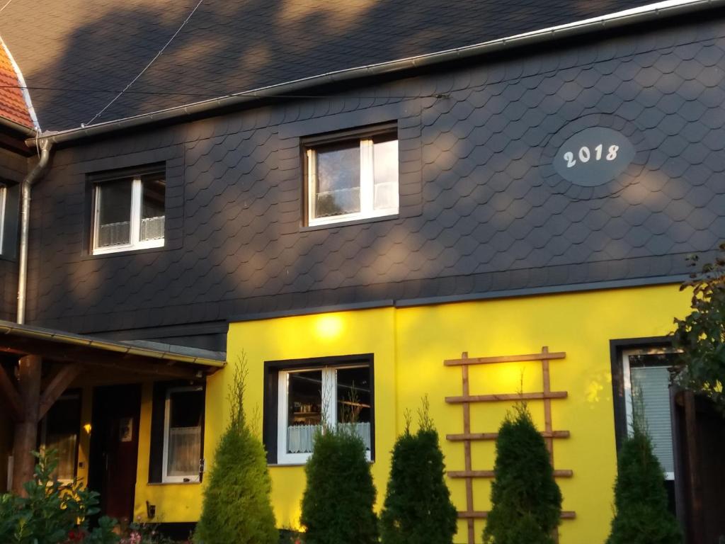a yellow and black house with a black roof at Ferienwohnung auf dem Land in Dittersbach