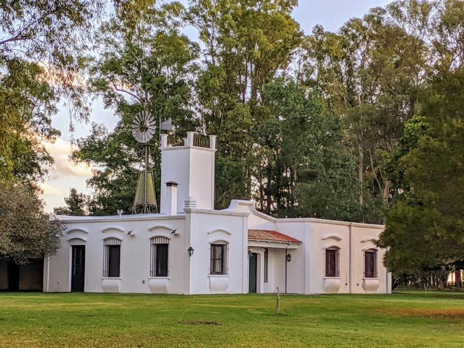 a white house with a clock tower on top of it at Estancia La Aurora, en Provincia de Buenos Aires in Azul