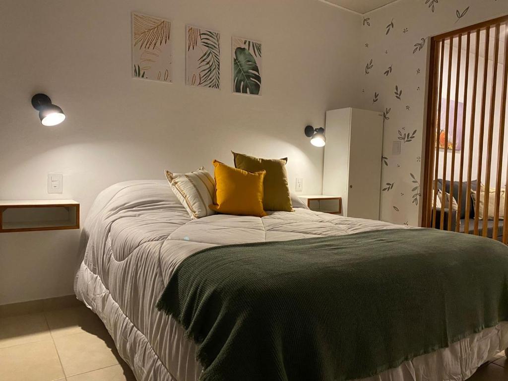 1 dormitorio con 1 cama grande con almohadas amarillas en Studio Estrada 2 Escobar en Belén de Escobar