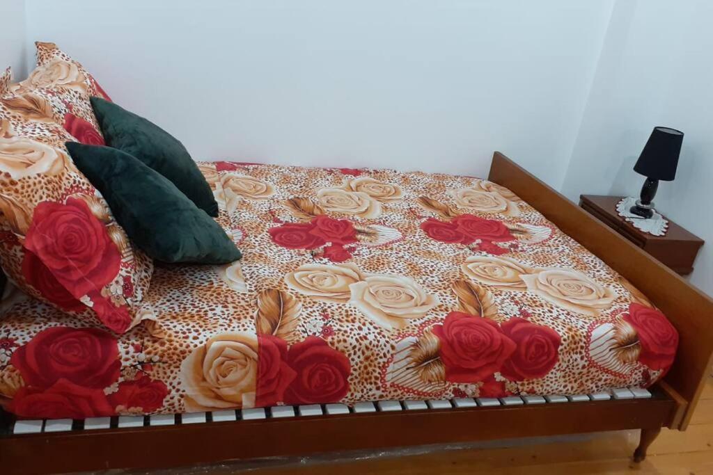 a bed with red and white flowers on it at Appartement Le Bonheur in Pibrac