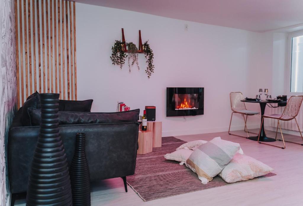 a living room with a black couch and a fireplace at La Villa Monroe - Un écrin de volupté épicée in Le Vézier