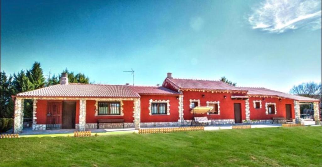 czerwony dom z zielonym trawnikiem przed nim w obiekcie Casa Bodegas Marcos w mieście Peñafiel
