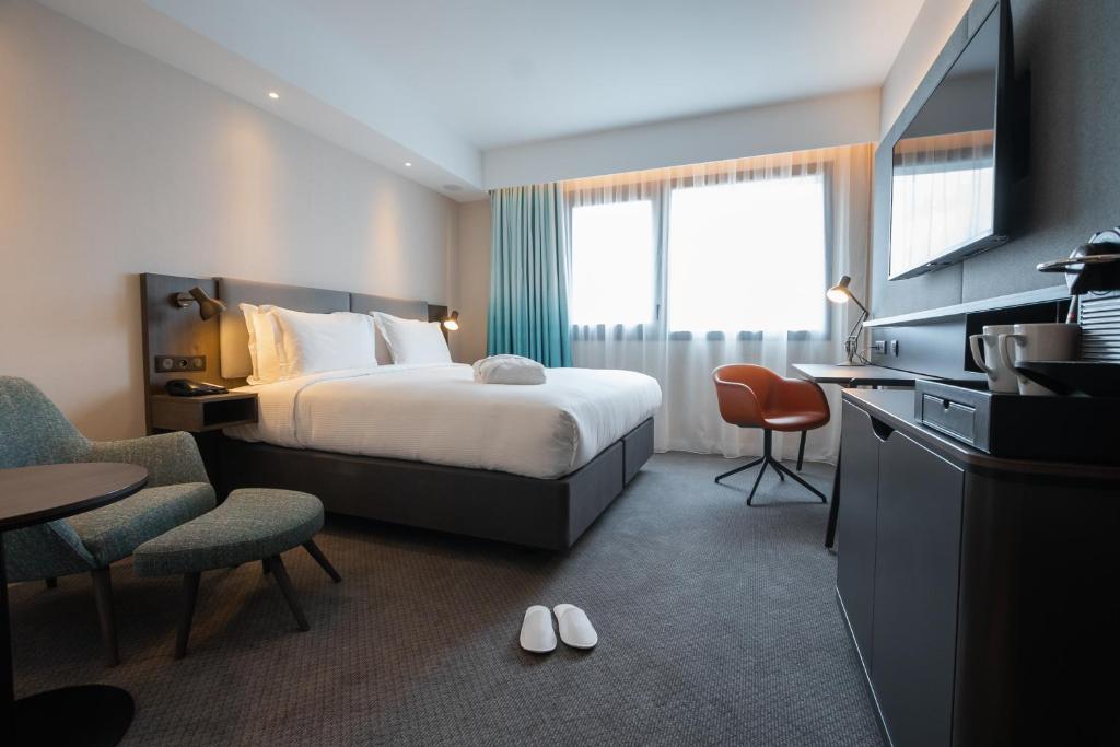 ロワシー・アン・フランスにあるHoliday Inn Paris CDG Airport an IHG Hotelのベッド、テーブル、椅子が備わるホテルルームです。
