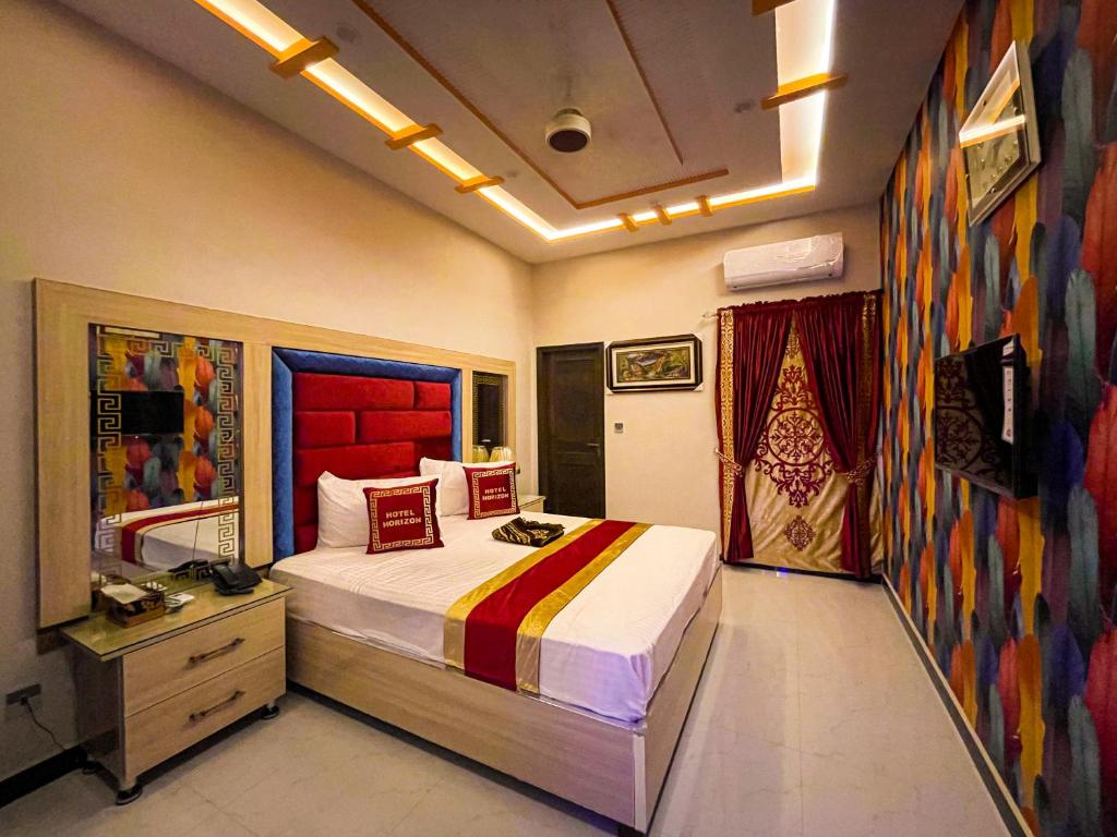ラホールにあるHorizon Hotelの大きなベッド付きのベッドルーム1室、壁に絵画が飾られています。