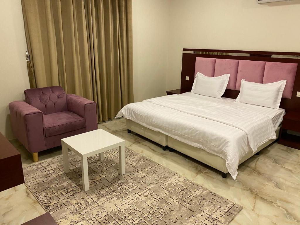 1 dormitorio con cama y silla morada en شقق القارات السبع الاحساء, en Al Hofuf