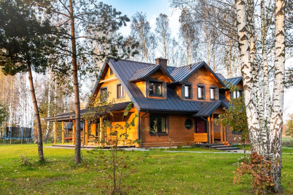 a large wooden house with a black roof at Żubrowe Sioło - dom nad łąkami in Białowieża