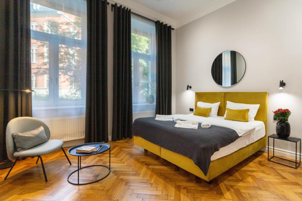 a bedroom with a king sized bed and a chair at Nola Apartments in Krakow