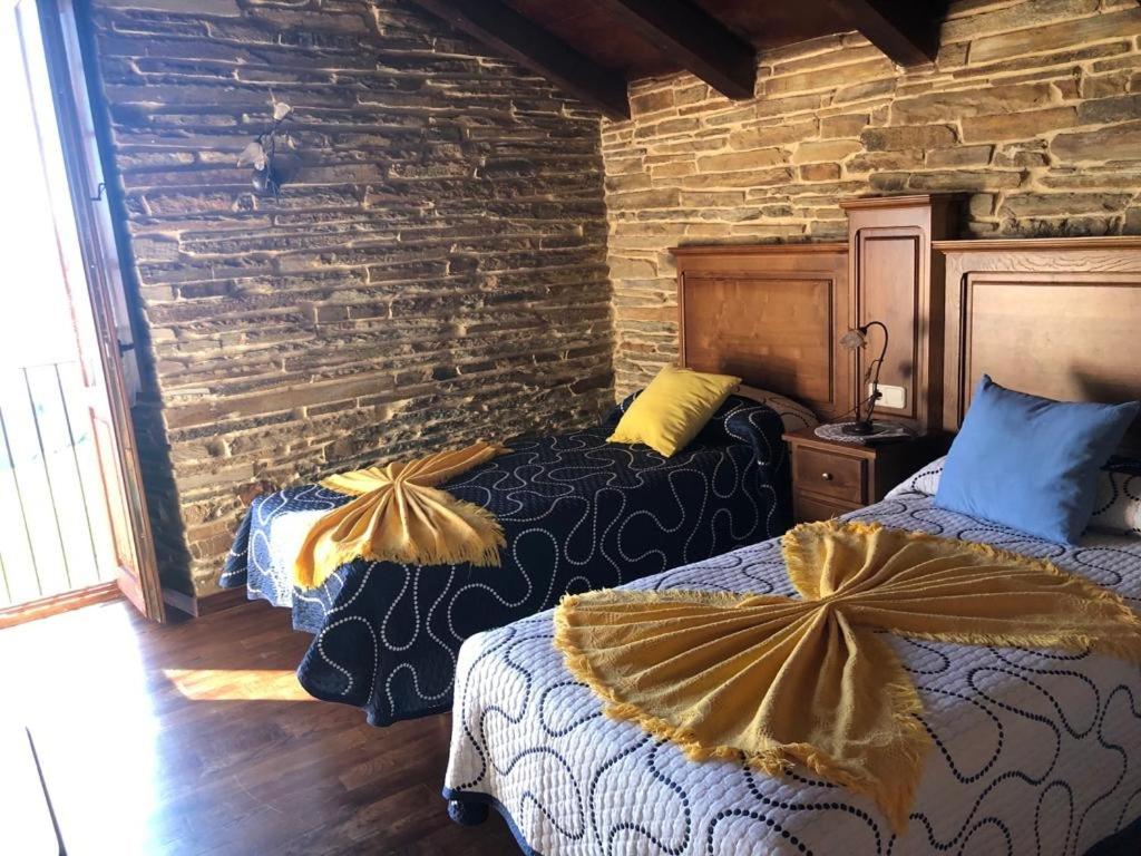2 camas en una habitación con una pared de ladrillo en La Posada de Oscos II en Santa Eulalia de Oscos