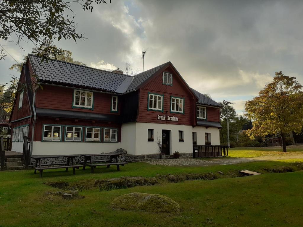 una casa roja y blanca con un banco delante en Chata Stará Brusírna, en Bedřichov