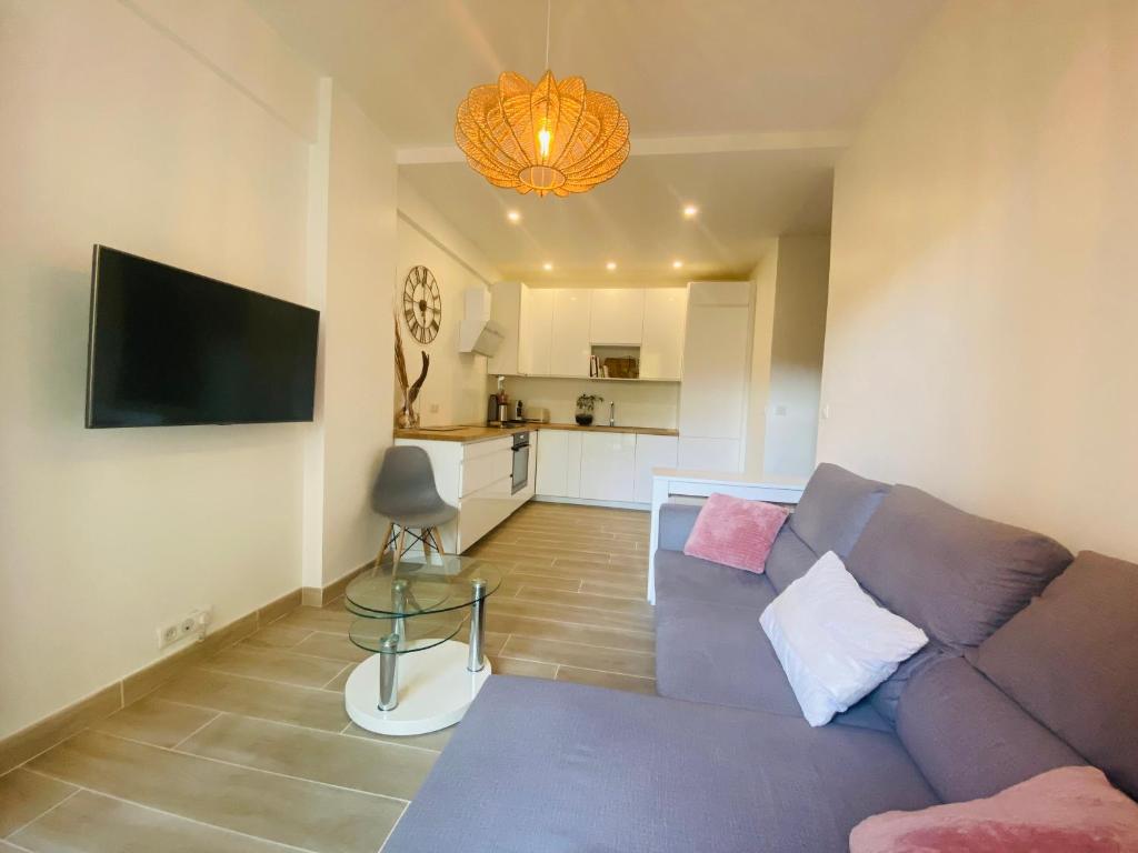 un salon avec un canapé violet et une télévision dans l'établissement 50m plage - 2 pièces jardin garage, à Cagnes-sur-Mer