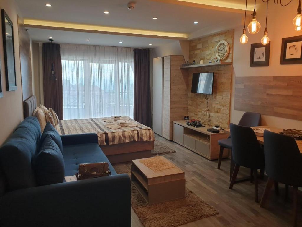 a living room with a blue couch and a bed at Milmari Premier40 in Kopaonik