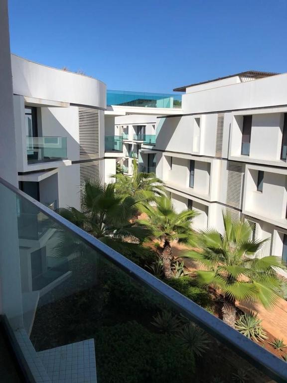a balcony with a view of a building with palm trees at Luxury Anfaplace Living Resort in Casablanca