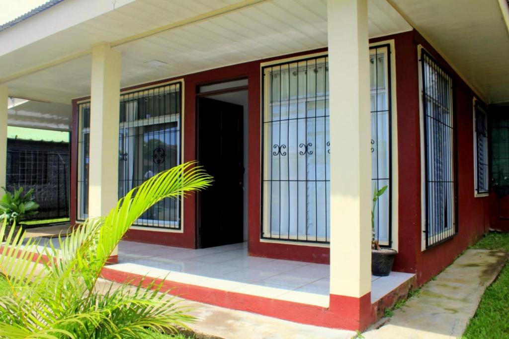 ein rotes Haus mit einer Veranda mit Glastüren in der Unterkunft Morpho Casa Vacacional in Fortuna