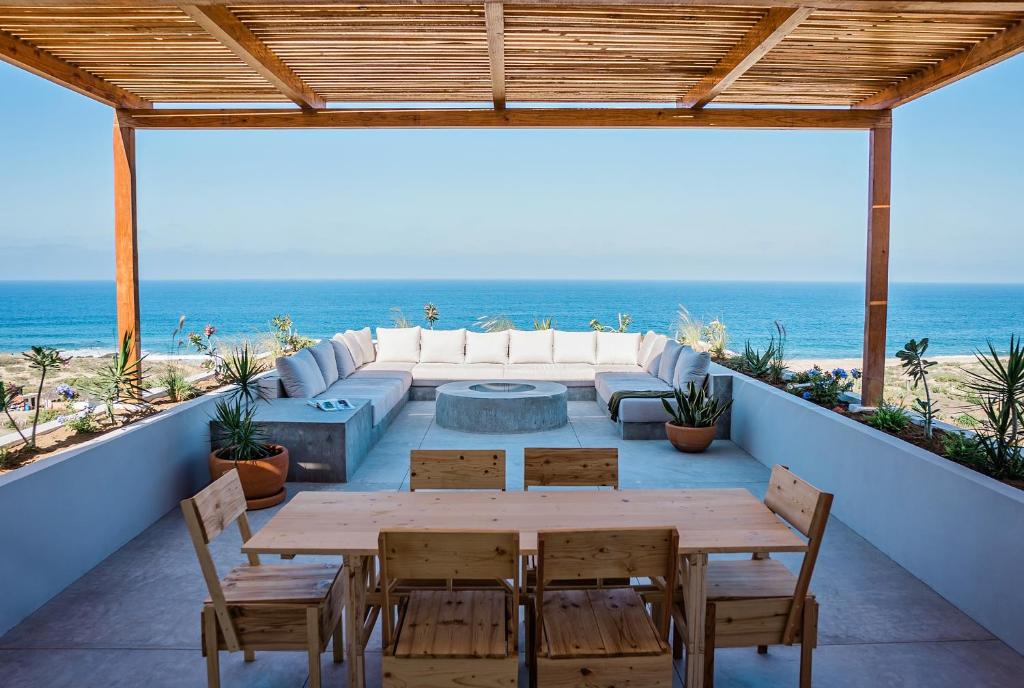 a patio with a table and chairs and the beach at Topia Retreat- Sunset Suite in El Pescadero
