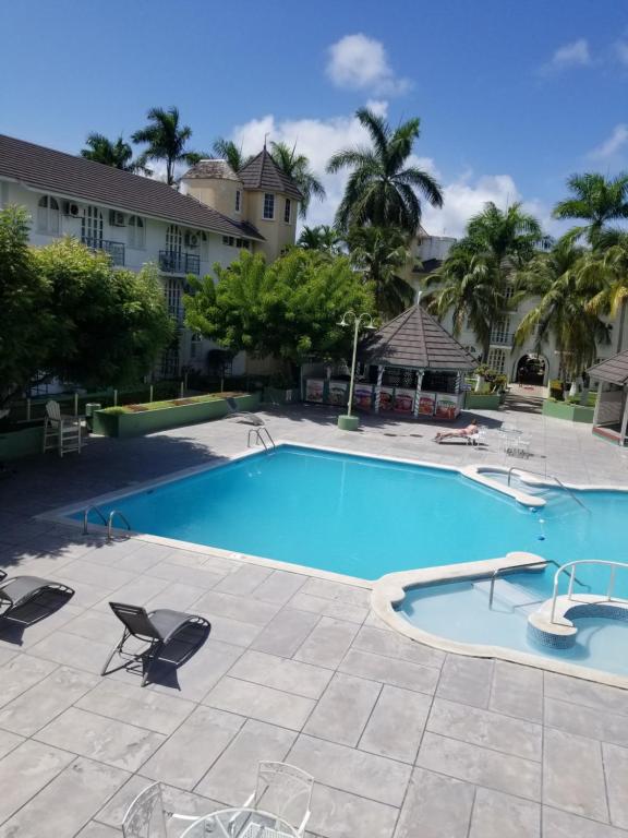 una grande piscina con sedie e palme di WINS On The Beach (@ Sandcastles Resort) a Ocho Rios