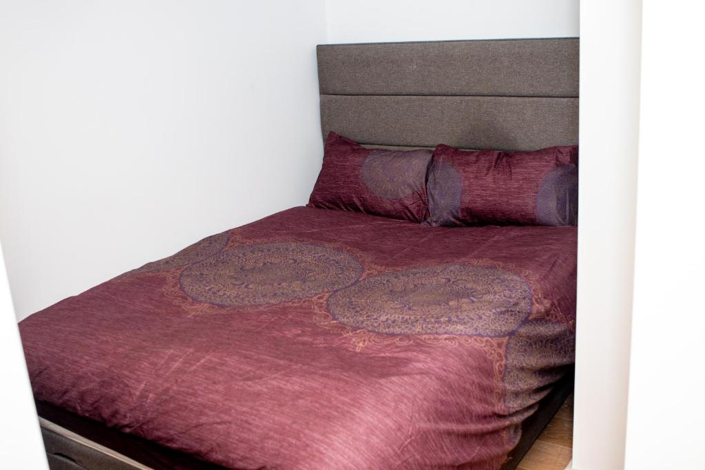 a bed with a purple blanket and pillows at Stunning 1-Bedroom flat in London! in London
