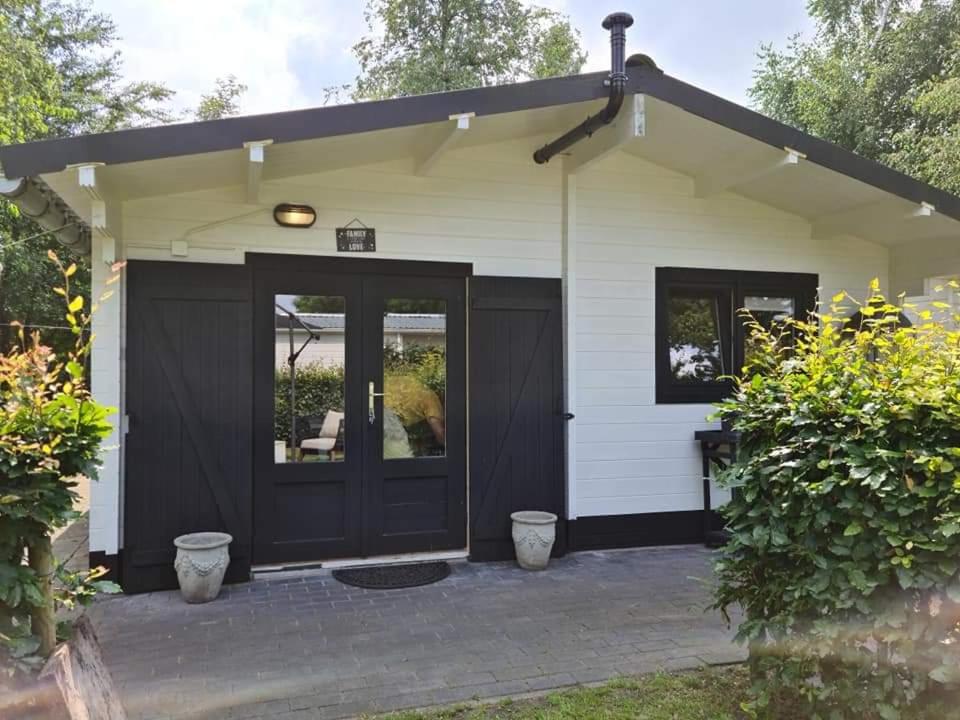 SchoonebeekにあるCasa Ibiza is vakantie in Drentheの黒いドアとパティオ付きの一戸建ての家