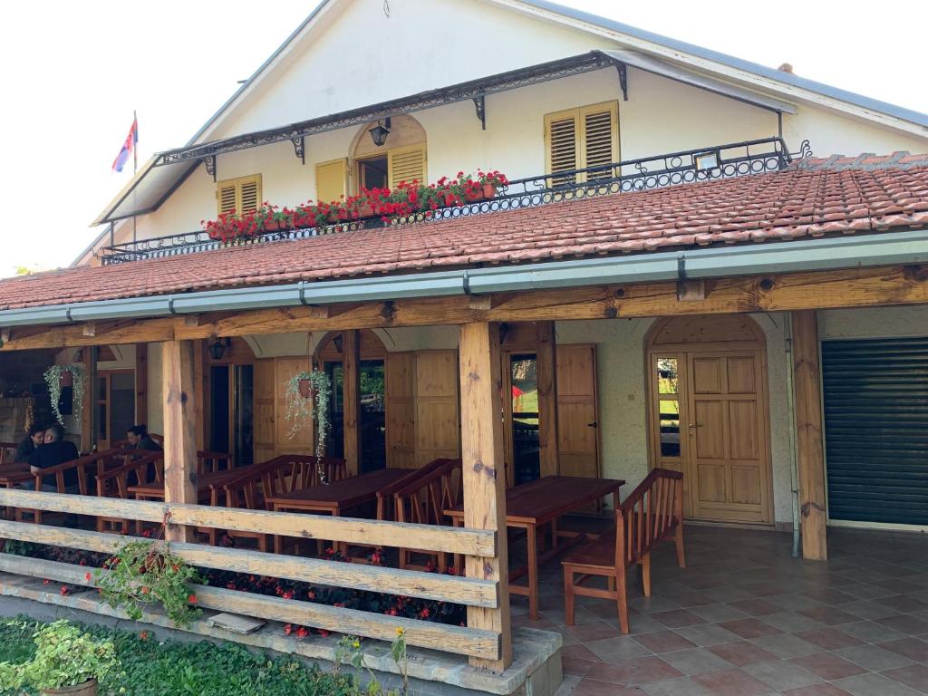 ein Restaurant mit Holztischen und -stühlen auf einem Gebäude in der Unterkunft Domaćinstvo Bakić in Irig