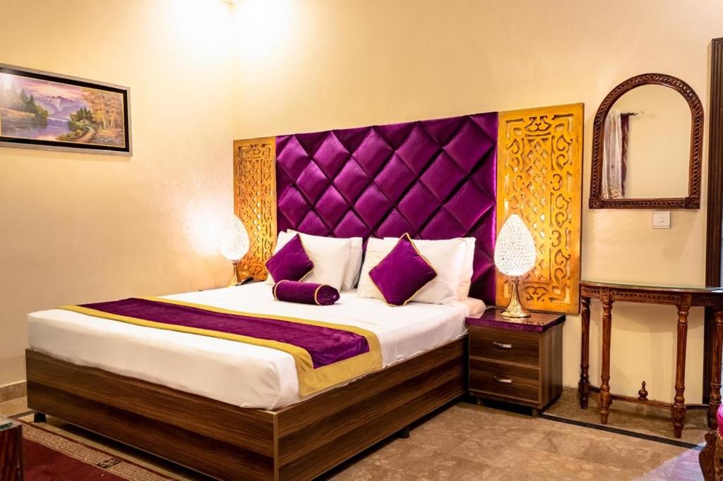 Schlafzimmer mit einem großen Bett mit einem lila Kopfteil in der Unterkunft Rose Palace Hotel, Gulberg in Lahore