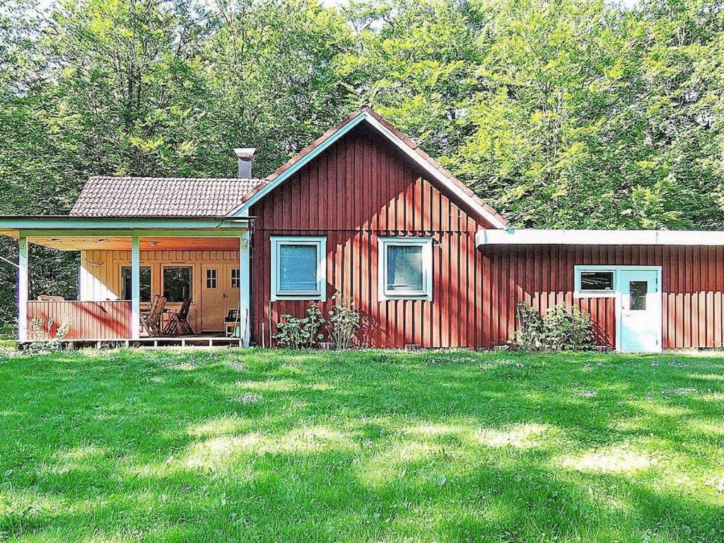 une maison rouge avec une terrasse couverte et une cour dans l'établissement 6 person holiday home in H STVEDA, à Hästveda