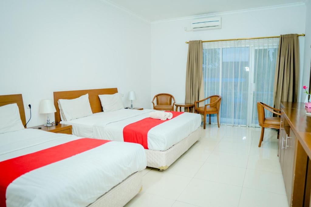 a hotel room with two beds and a table at HOTEL & WISMA BINTANG JADAYAT in Bogor
