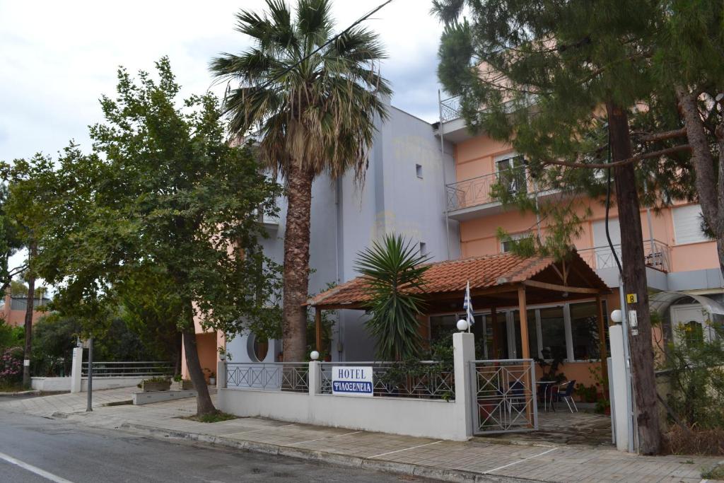 a white building with a porch and palm trees at Filoxenia Hotel in Volos