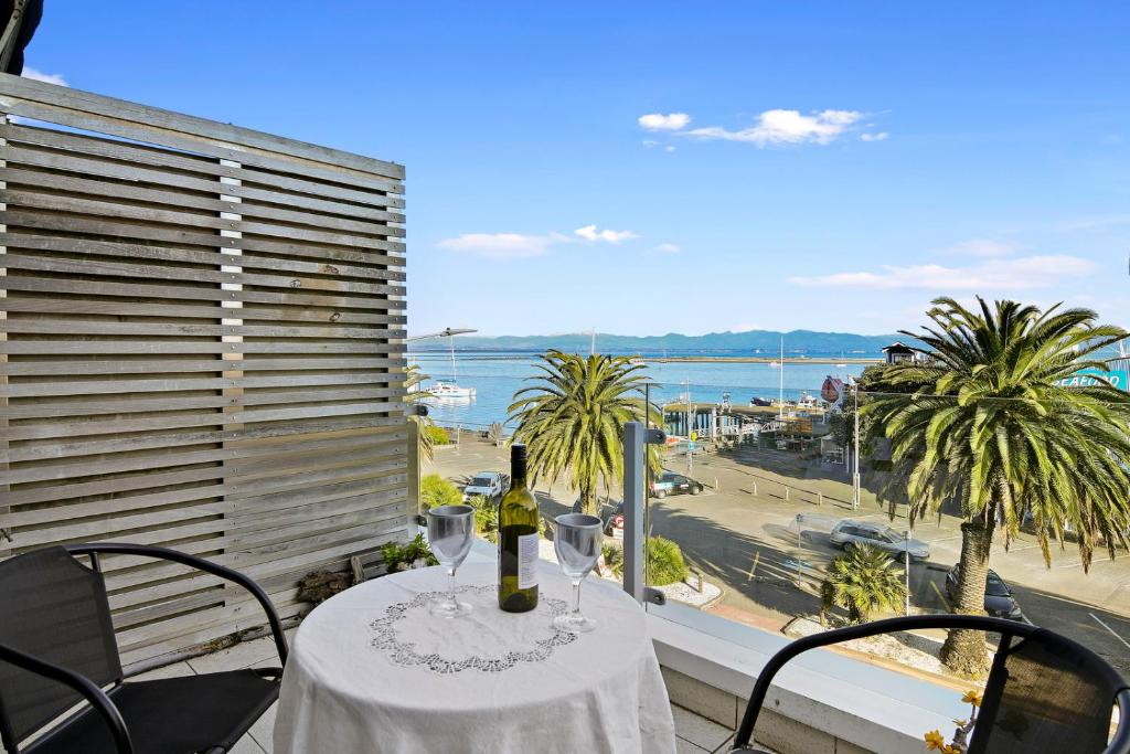 a table with wine glasses and a view of the ocean at Wakefield Wonder - Nelson Holiday Apartment in Nelson