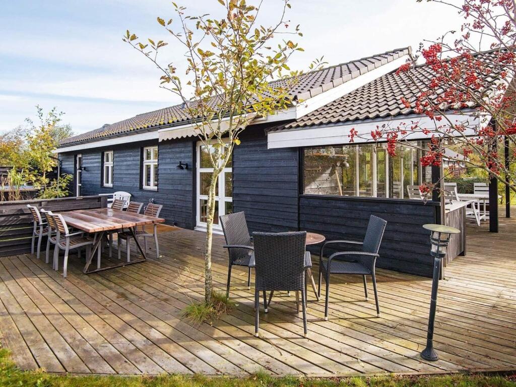 a deck with a table and chairs and a house at 6 person holiday home in Tarm in Hemmet