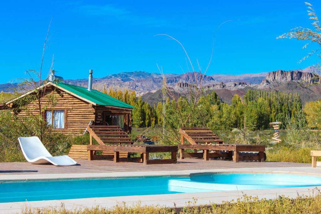 a log cabin with benches and a pool at Inca Roca in Uspallata