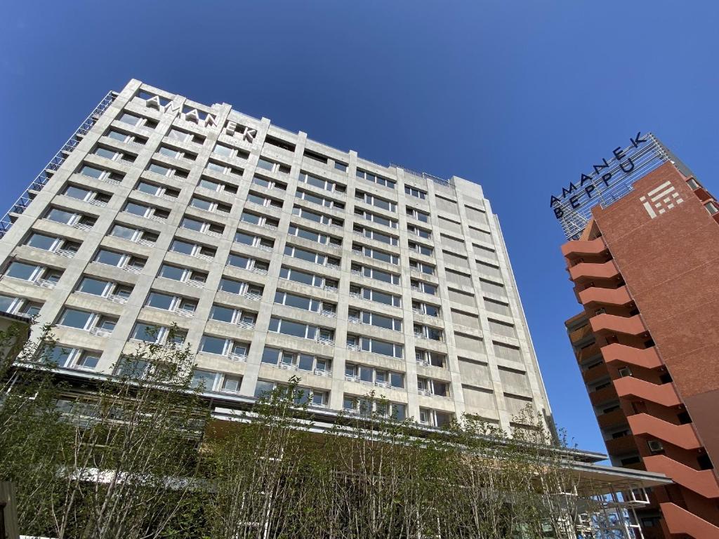 a tall white building with two tall buildings at AMANEK Beppu YULAｰRE in Beppu