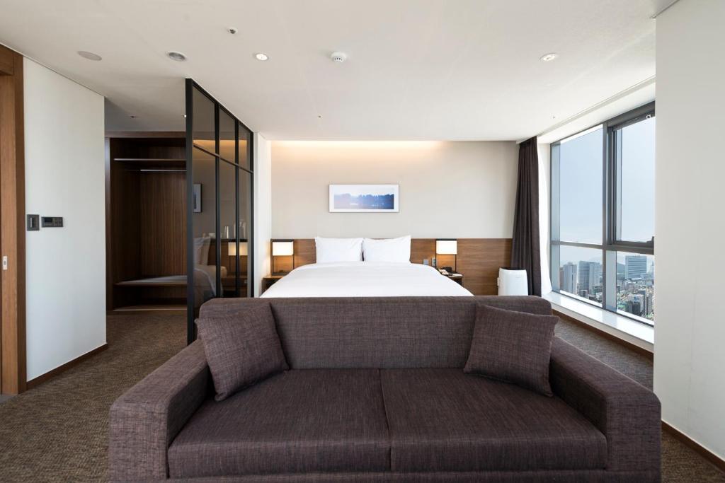 釜山にあるRamada Encore by Wyndham Busan Haeundaeのベッドとソファ付きのホテルルーム