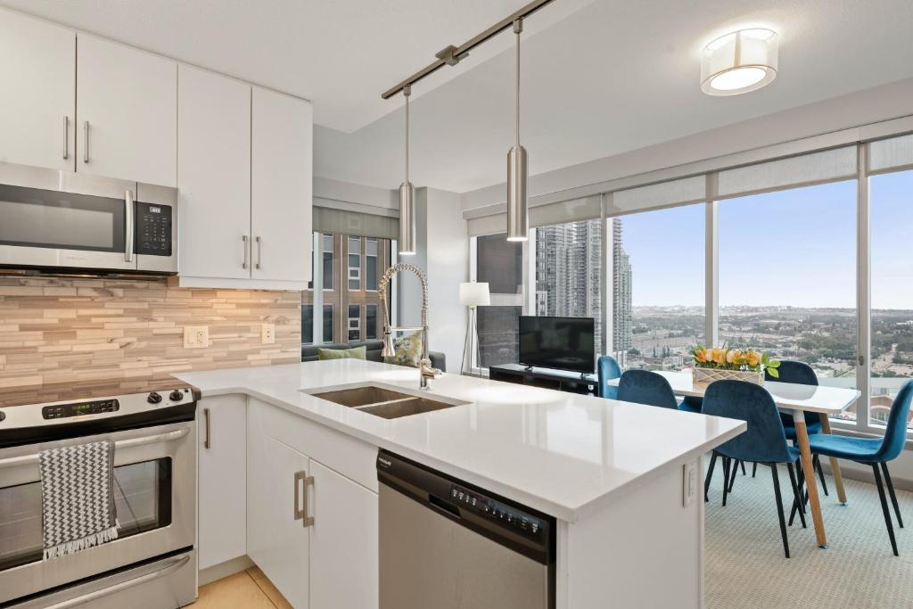 una cocina con armarios blancos y una mesa con sillas. en Stylish Downtown Condos by GLOBALSTAY, en Calgary