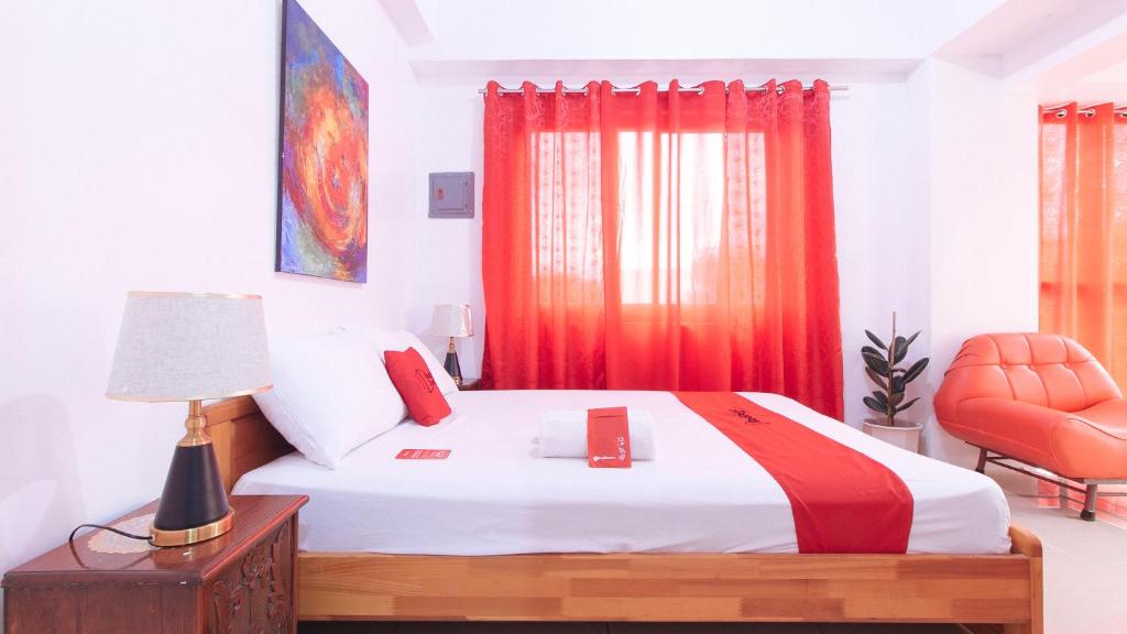 a bedroom with a bed and a red chair at RedDoorz near LRT 2 Antipolo Station in Antipolo