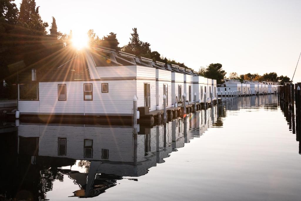 a row of houses on a dock in the water at The Sea Lodges Portoroz - Bootshaus Floating Sea House in Portorož