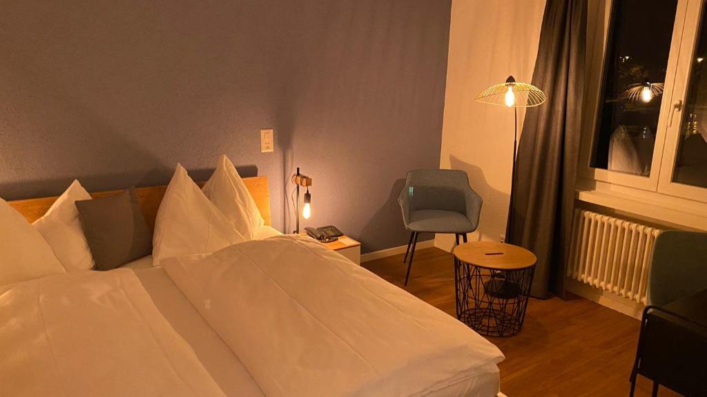 una camera con un letto bianco e una sedia di Gasthof zum Schützen ad Aarau