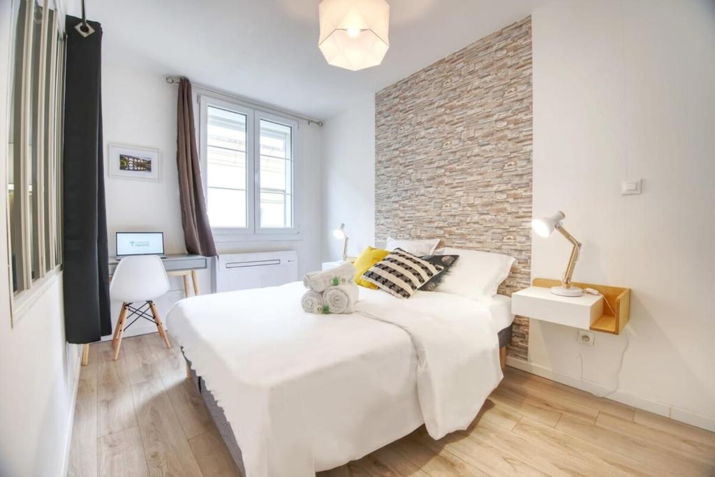 a bedroom with a white bed and a brick wall at La Balade Nîmoise Center Car Park AC in Nîmes