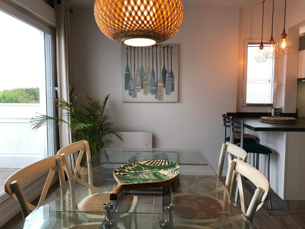 une salle à manger avec une table et des chaises en verre dans l'établissement PERLIERES T2 lumineux vue bassin parking wifi, à Arcachon