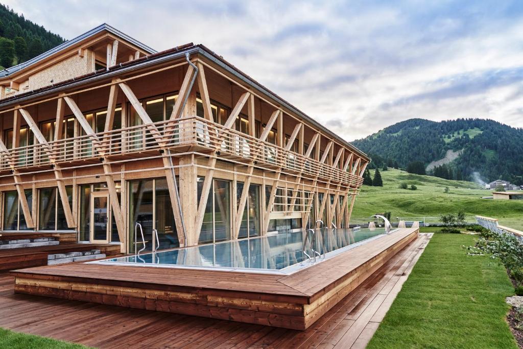 una casa de madera con piscina frente a ella en HUBERTUS Mountain Refugio Allgäu en Balderschwang