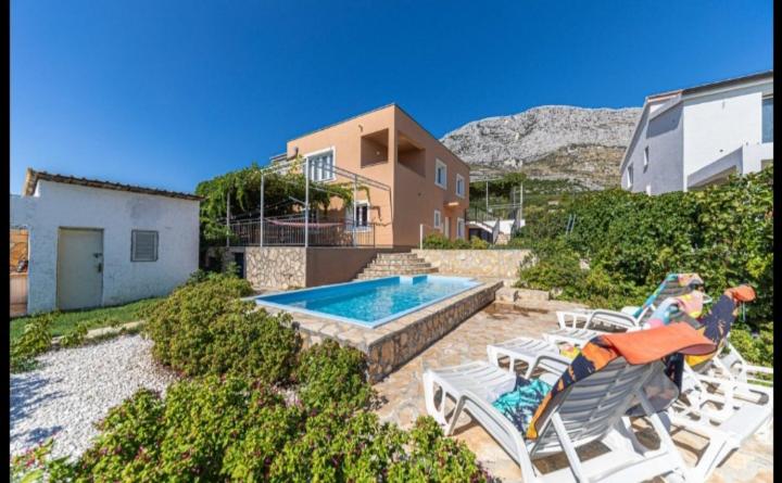a house with a swimming pool and some chairs at Apartman Marinović in Kaštela